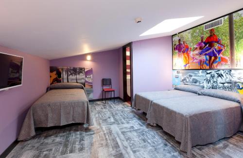2 camas en una habitación con paredes moradas en JC Rooms Chueca, en Madrid