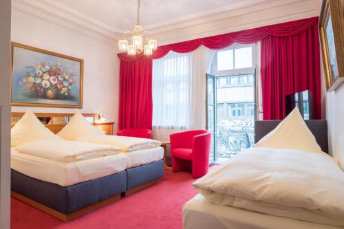ミュンヘンにあるホテル バイエルンランドのベッド2台とシャンデリアが備わるホテルルームです。