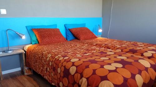 a bedroom with a bed with orange comforter and red pillows at o vale da mudança in Monte da Pedra Alva