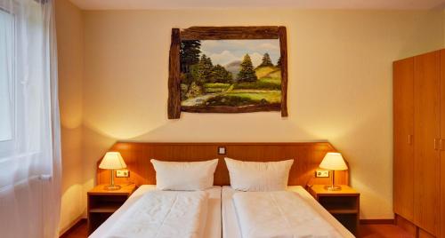 a bedroom with two beds and a painting on the wall at Hotel Harzlodge in Goslar