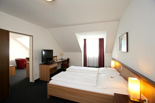 Schlafzimmer mit einem großen weißen Bett und einem Schreibtisch in der Unterkunft Christkönigshaus in Stuttgart