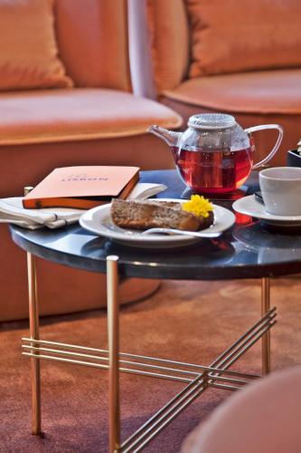 a table with a plate of food and tea on it at Altis Avenida Hotel in Lisbon