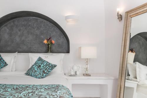 a bedroom with a white bed and a mirror at Anteliz Suites in Fira