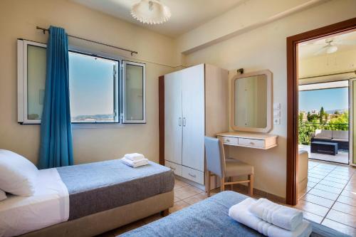 a bedroom with two beds and a desk and a mirror at Dionysos Village Resort in Lassi