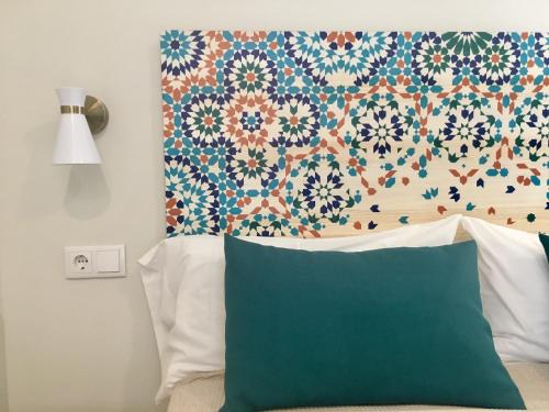 a bed with a green pillow and a floral headboard at MD Design Hotel - Portal del Real in Valencia