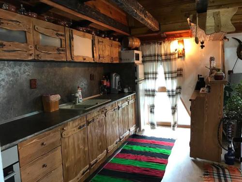 a kitchen with wooden cabinets and a colorful rug at Guest Rooms Profirov in Zlatograd