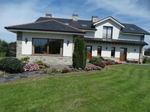 a white house with a yard at Apartamentos La Cruz de Paderne in Navia