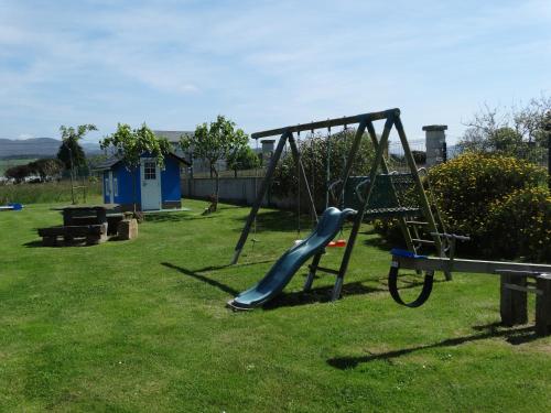 a playground with a slide in the grass at Apartamentos La Cruz de Paderne in Navia