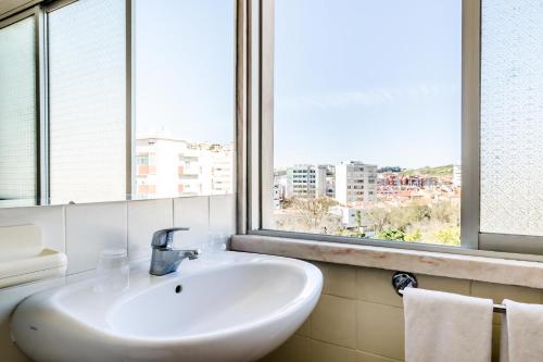a white sink in a bathroom with a window at Residencial Jardim da Amadora in Amadora