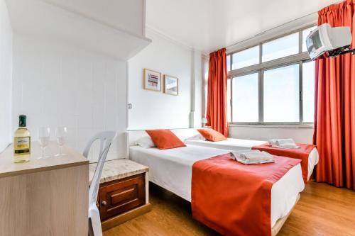 a bedroom with two beds with red curtains and a kitchen at Residencial Jardim da Amadora in Amadora
