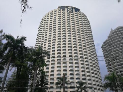 a large white building with palm trees in front of it at VIP condo rayong in Ban Phe