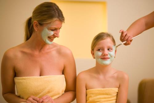 a woman cutting a little girls face in a mirror at Allegria Resort Stegersbach - Allegria Hotel in Stegersbach