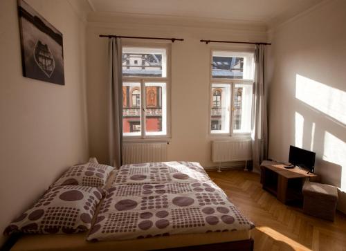 a bedroom with a bed and two windows at Carpe Diem Prague in Prague