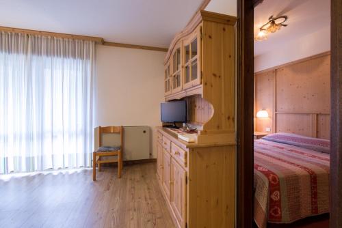 une chambre avec un lit et une télévision sur une commode dans l'établissement Residence Edelweiss, à San Martino di Castrozza
