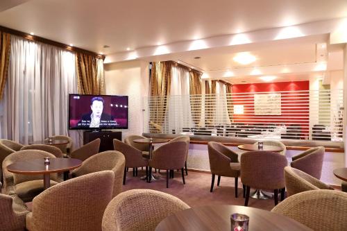 a waiting room with tables and chairs and a television at Boutique Hotel Parnassia in Arachova