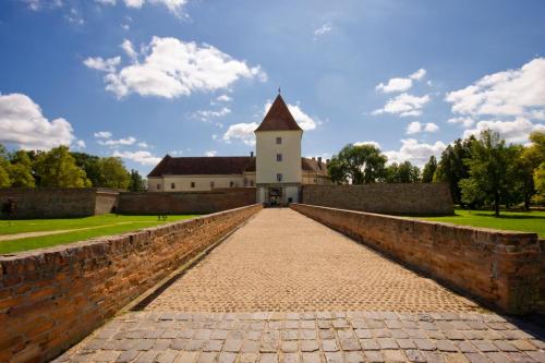 a brick bridge leading to a building with a tower at Atmoszféra Apartman in Sárvár