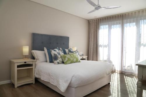a bedroom with a large white bed with blue pillows at Cape Coral in Hermanus