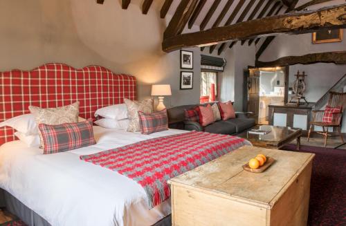a bedroom with a large bed with a wooden table at The Lygon Arms - an Iconic Luxury Hotel in Broadway