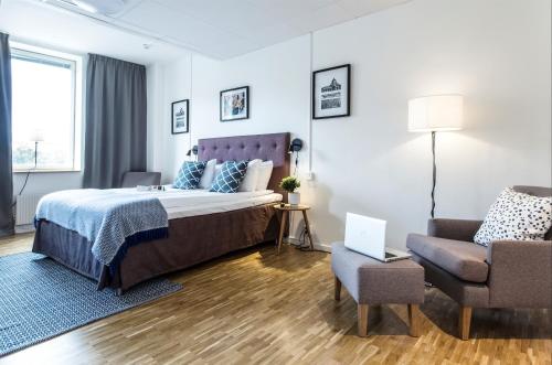 Biz Apartment Solna في سولنا: غرفة نوم بسرير واريكة وكرسي