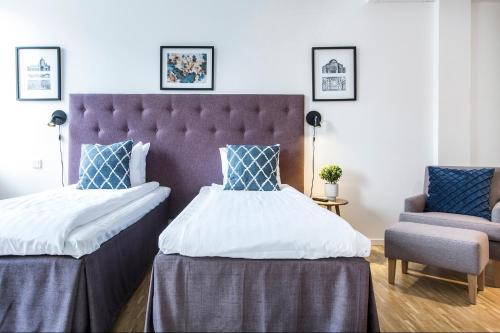 a bedroom with two beds and a chair at Biz Apartment Solna in Solna