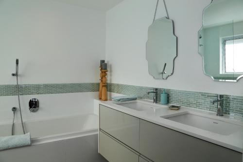 a white bathroom with two sinks and a mirror at Cape Coral in Hermanus
