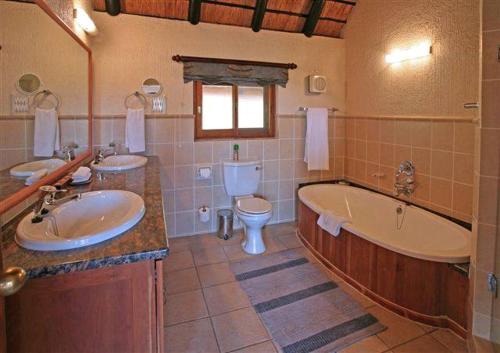 een badkamer met een bad, een wastafel en een toilet bij Kruger Park Lodge 401 in Hazyview