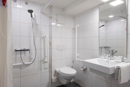 y baño blanco con ducha, aseo y lavamanos. en Hotel Vadian Garni, en St. Gallen
