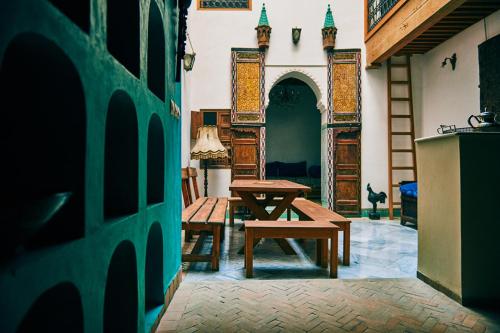 een patio met een houten tafel en een bank in een kamer bij Dar Saida in Fès