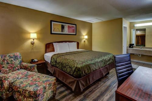 ein Hotelzimmer mit einem Bett und einem Stuhl in der Unterkunft Kingsway Inn Corsicana in Corsicana