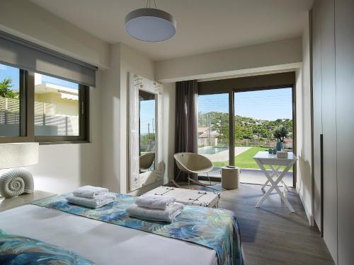 a bedroom with a bed and a desk and windows at Elaia Luxury Suites Lagonisi in Lagonissi