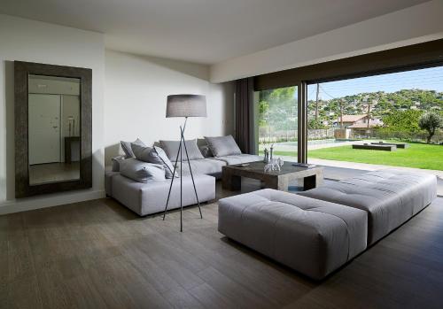a living room with two couches and a table at Elaia Luxury Suites Lagonisi in Lagonissi