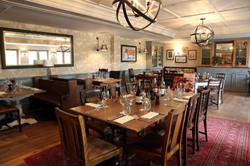 a restaurant with wooden tables and chairs and a chandelier at The Foley in Claygate