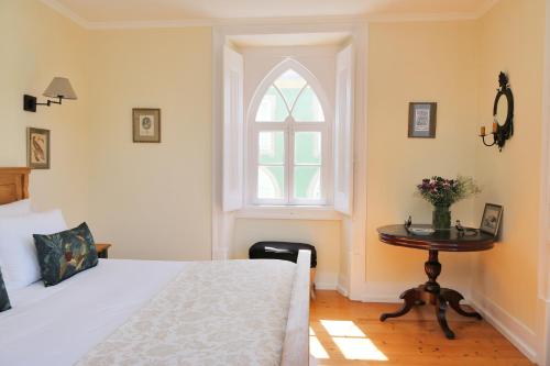 a bedroom with a bed and a table with a window at Casa Holstein Quinta de Sao Sebastiao Sintra in Sintra