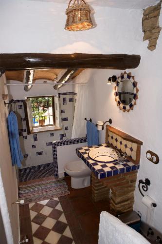 a bathroom with a toilet and a checkered floor at El Huertecillo in Arriate