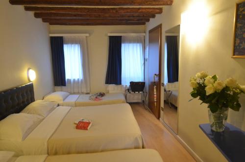 a hotel room with two beds and a vase of flowers at Piccolo Tiepolo in Venice