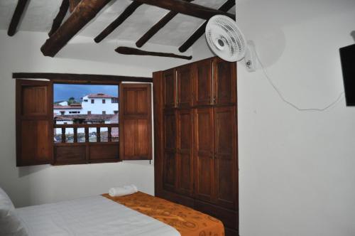 a bedroom with a bed and a window with a fan at Hospedaje Donde Lorenzo in Barichara