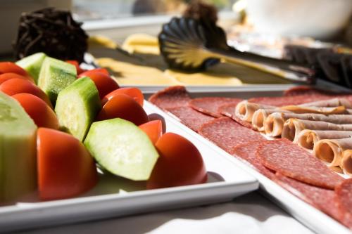 un buffet di cibi con carne e verdure su piatti di Court Inn a Panagyurishte