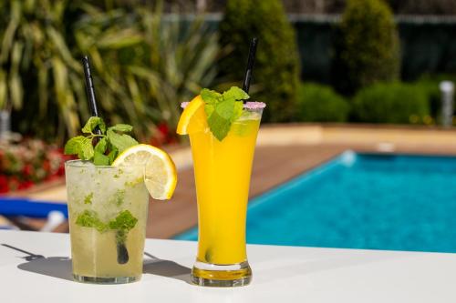 two drinks sitting on a table next to a pool at Hotel Desitges in Sant Pere de Ribes