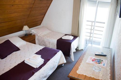 a hotel room with two beds and a table at Hotel Colón in Piriápolis