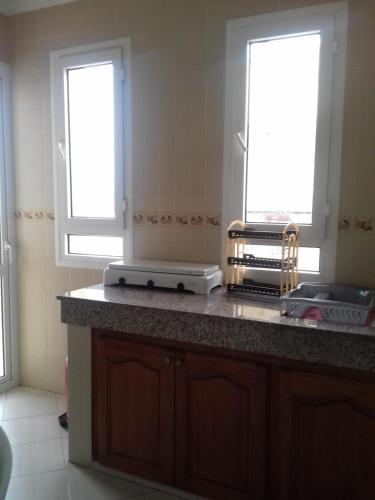 a kitchen with two windows and a counter top at Résidence La Galiote in Essaouira