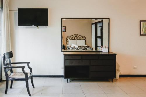 a mirror on a dresser in a room with a chair at Hotel Colon Merida in Mérida