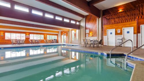 a swimming pool with tables and chairs in a building at Best Western Ambassador Inn & Suites in Wisconsin Dells