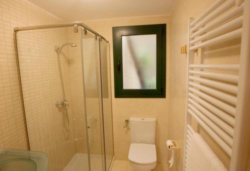 a bathroom with a toilet and a glass shower at Cal Metge de Gualba in gualba de Dalt