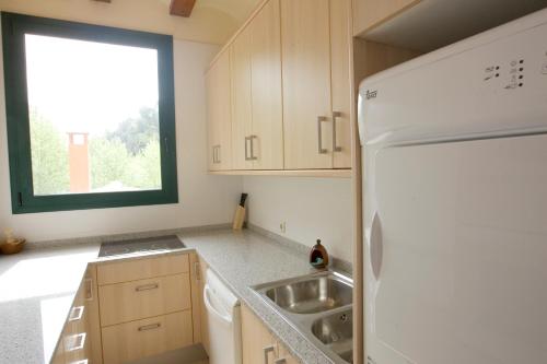 a kitchen with a white refrigerator and a sink at Cal Metge de Gualba in gualba de Dalt