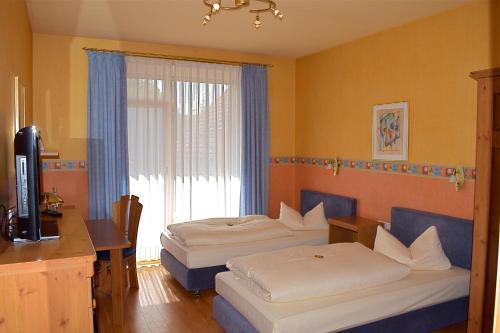 a hotel room with two beds and a desk at Landgasthof Buch in Eichenzell