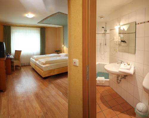 a bedroom with a bed and a bathroom with a sink at Landgasthof Buch in Eichenzell
