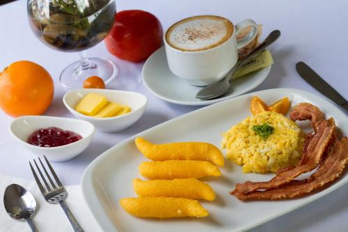 a plate of breakfast food with bacon and eggs and a cup of coffee at Los Brezos Hotel Boutique in Volcán
