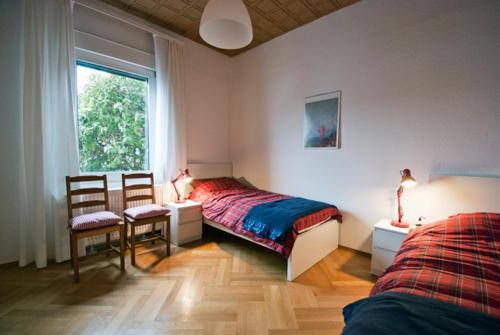 1 dormitorio con 1 cama, 2 sillas y ventana en Sieben Linden, en Remscheid