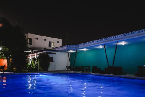 a blue swimming pool at night with a building at Hotel Colon Merida in Mérida