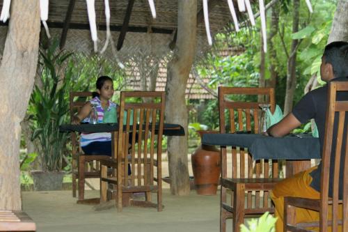 a woman sitting at a table in a restaurant at A4 Villa & Spa. in Habarana